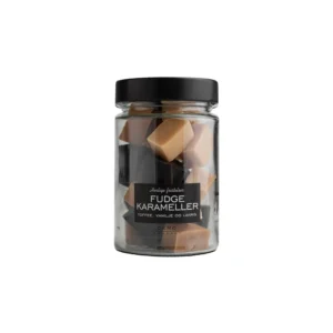 Gjennomsiktig glass med sort lokk. Glasset er fylt med fudgekarameller
